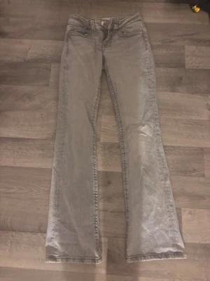 Grå bootcut jeans från Perfect Jeans - Säljer ett par grå jeans från Perfect Jeans i storlek 32. Modellen har bootcut-snitt och klassiska fem fickor, med snygga detaljer på bakfickorna och silverfärgade knappar. Jeansen är tillverkade i mjukt denim-material och har en normal passform.