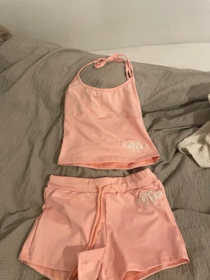 Set ljusrosa linnetopp och shorts från Shein XS - Säljer en ljusrosa linnetopp och shorts från Shein i storlek XS. Toppen har smala axelband med knyt i nacken och är dekorerad med vit broderad detalj framtill. Materialet på båda är mjuk polyester med lite stretch för skön passform.