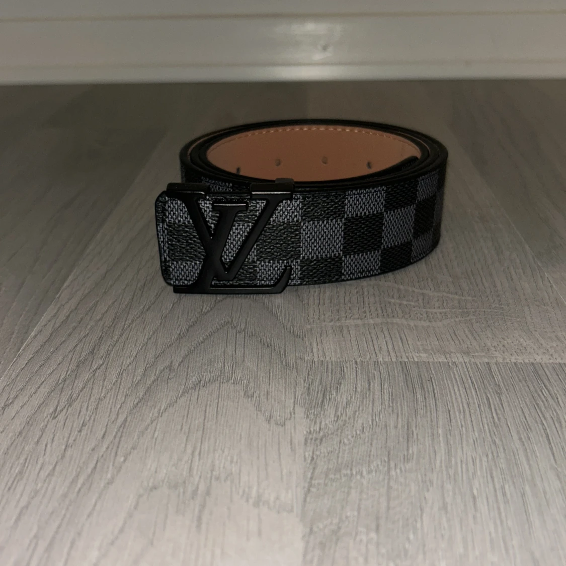 Ett svart bälte med svart logga från Lindex