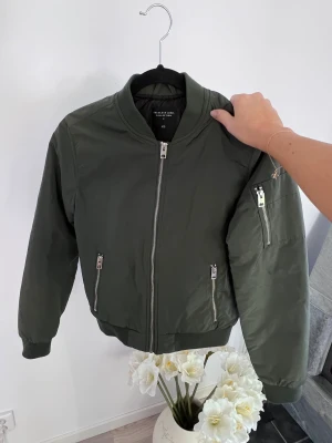 Mörkgrön bomberjacka från Lager157, storlek XS  - En mörkgrön bomberjacka från Lager157 i storlek XS 💚 Mycket sparsamt använd 🌷  Mått: Längd: 62 cm Axel: 39 cm  - Köper du innan kl 16:00 kan jag skicka samma dag!