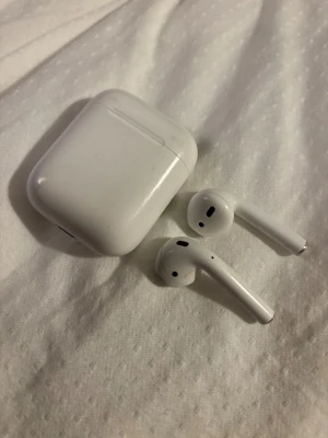 Apple AirPods (2nd generation) - Säljer ett par Apple AirPods (2nd gen) med laddningsetui. Hörlurarna är trådlösa och fungerar utmärkt, batterinivåerna är goda. Viss kosmetisk slitage syns på etuiet, men inget som påverkar funktionen. Perfekt för musik, samtal och träning.