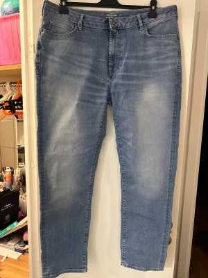 Dressmann ljusblå jeans tailored fit strl: 40/30 - Snygga ljusblå jeans från Dressmann i modellen tailored fit. Klassisk femficksdesign, raka ben och normal passform. Jeansen har subtila slitningar framtill och är tillverkade i mjukt denimtyg som är skönt att bära hela dagen. Prislappen är bortklippt. Byxorna är endast prövade ej använda.