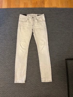 Ljusgrå skinny jeans från Dondup - Snygga ljusgrå jeans från Dondup, modell George Skinny Fit. De har klassisk femficksdesign, smal passform och raka ben. Jeansen är tillverkade i mjukt denim och har diskreta sömmar samt logotypdetalj på bakfickan. Perfekta för en clean och modern look.