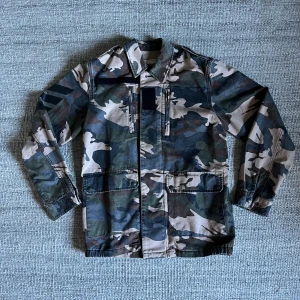 Camouflage jacka från Zadig & Voltaire - Snygg camouflagejacka från Zadig & Voltaire med klassisk krage, knappar och dragkedja. Jackan har flera fickor. Perfekt för dig som behöver en stilren och unik jacka inför hösten. Skicket är superbra - 9/10. Tveka aldrig att fråga om du har någon fundering. Nypris på jackan är ca 400€ ≈ 4000kr. 
