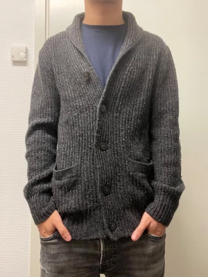 Stickad cardigan - Fet mörkgrå stickad cardigan från H&M. Väldigt bra skick. Modellen är 173cm, 64kg. Pris kan diskuteras!