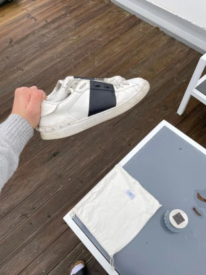Valentino Open sneakers vit/svart - Säljer ett par Valentino Opens med svart rand. Skorna är i använt skick ingår: skor och dustbag. Kan garantera äkthet. Kolla sista bild för att se mest omfattande defekten