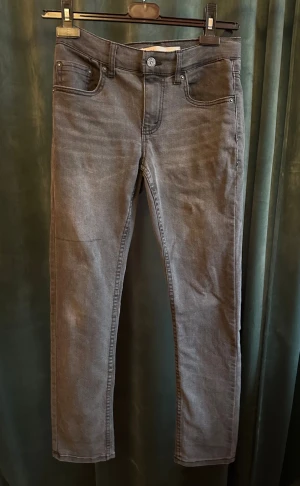 Levi's 512 Slim Taper grå jeans - Snygga grå Levi's 512 Slim Taper jeans med klassisk femficksdesign och smal, avsmalnande passform. Jeansen har en mörkgrå ton, diskreta sömmar och är tillverkade i mjukt jeansmaterial. Perfekt för dig som gillar stilrena och moderna jeans. Str 12A elr runt 164kr. Pris 249kr helt okej skick 