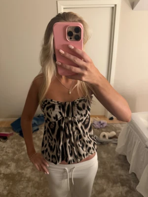 Leopardmönstrad tubtopp från Amisu - Säljer en snygg tubtopp från Amisu med leopardmönster i beige, svart och bruna toner. Toppen är bandeau-modell, har elastisk kant upptill och nedtill för bra passform och är tillverkad i mjuk polyester. Perfekt för dig som vill sticka ut med ett djuriskt print.