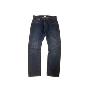 Grant 405 mörkblå jeans straight fit - Mörkblå jeans från Grant, modell 405, med klassisk femficksdesign och raka ben. Jeansen har snygga kontrastsömmar och patch bak i midjan. Tillverkade i slitstark denim som ger en tidlös look. Perfekta för dig som gillar enkel och stilren stil.