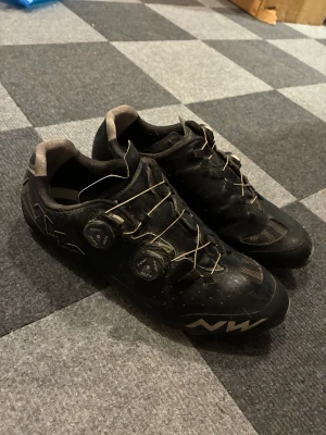 Svarta cykelskor från Northwave - Säljer ett par svarta cykelskor från Northwave med snygga detaljer och två snörningsrattar för perfekt passform. Skorna har ventilerande meshpartier och en låg profil som passar för dig som gillar att cykla med stil. NW-logga på sidan och tå.
