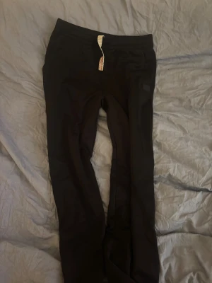 Svarta mjukisbyxor med snörning - Svarta mjukisbyxor med elastisk midja och vit snörning. Byxorna har en enkel och clean look med en liten patch på ena benet. Perfekta för chill dagar eller när du vill vara bekväm men ändå se snygg ut. Ny pris är 2500 