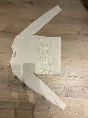 Beige stickad tröja med spets från Zara strl S - Supersöt beige tunn stickad tröja från Zara i storlek S. Tröjan har lång ärm och ett brett parti med blommig spets framtill som ger en extra detalj. Rund halsringning och mjukt material som känns skönt mot huden. Perfekt för dig som gillar romantiska vibes. 💗