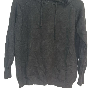 Svart merinoull hoodie med huva - Mysig svart marinoull hoodie med huva och dragsko. Tröjan har långa ärmar. Är 40cm bred 50cm lång.