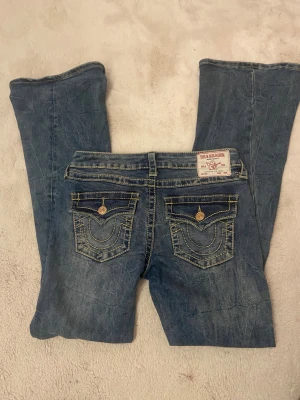 True Religion Joey Low Rise Flare jeans - Säljer ett par blå True Religion Joey Low Rise Flare jeans med snygga flaps! Ny pris: 1800kr på jeans Uno!