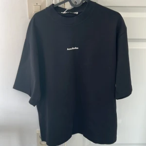 Svart t-shirt Acne Studios - Svart t-shirt från Acne Studios med vit logo