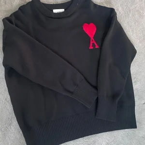 AMI Paris Ami Crewneck Jumper Stl. M - Svart stickad tröja från Ami med rund hals och ribbade muddar. Tröjan har lång ärm och en clean, klassisk look som känns både trendig och chill. Nytt skick och helt oanvänd. Storlek M.