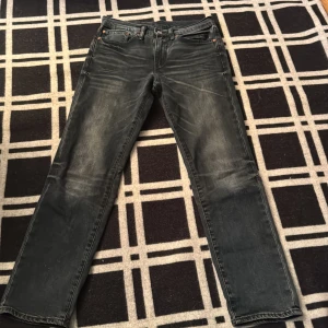 Levi's 511 svarta jeans  - Säljer ett par svarta Levi's 511 jeans med snyggt tvättad look. Modellen är slim fit med klassiska fem fickor, dragkedjegylf och den ikoniska läderpatchen bak. Jeansen har en något blekt finish och är tillverkade i bomull med lite stretch för skön passform.