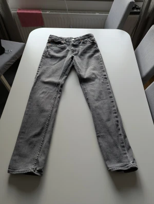 Grå Levi's 511 jeans straight fit - Säljer ett par grå Levi's 511 jeans med klassisk femficksdesign och raka ben. Jeansen har en snygg tvättad look, normal passform och är tillverkade i mjukt bomullsjeansmaterial. Perfekt för dig som gillar stilrena och tidlösa jeans. OBS: Liten reva vid bakfickan som kan lagas (se sista bild).