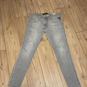 Replay Anbass grå slim jeans - Snygga grå Replay Anbass jeans med slim fit och klassisk femficksdesign. Jeansen har diskreta detaljer och logotyp på fickan, raka ben och bekväm passform. Perfekt för dig som gillar stilrena och moderna jeans. Jeansen är knappt använda då jag inte tyckte dom var snygga på mig. 