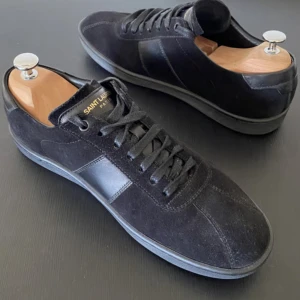 Mocka Saint Laurent low trainers strl 42 - Saint Laurent Lowtrainers i storlek 42 i mocka, sällsynta och sällan man ser de, äldre modell men inte mycket använda, de har lite smuts på sig i bilderna och ett skosnöre än sönder men det är lättfixat. Första bilden är inte nuvarande skick men går lätt att putsa upp de i det skicket med tvätt och nytt skosnöre. Sista bilden är äkhetsbevis från vestiare