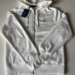 Polo Ralph Lauren zip hoodie  - Snygg vit hoodie från Polo Ralph Lauren, Storlek M, aldrig andvänd, frågor eller funderingar är det bara att höra av dig. Prisset ej hugget i sten.