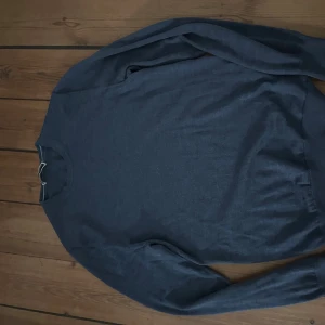 Mörkgrön stickad tröja Oscar Jacobson - Snygg mörkgrön stickad merinoull tröja från Oscar Jacobson i storlek S. Tröjan har rund hals och långa ärmar med ribbade muddar vid ärmslut och nederkant. Perfekt för dig som gillar stilrena och klassiska plagg med en modern touch.