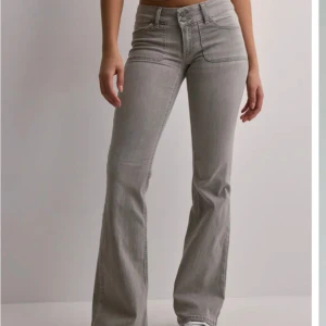 Grå bootcut jeans med låg midja - Snygga grå jeans med bootcut och låg midja.Dem är strlk 32 och köpta från Nelly💕  34cm tvärsöver i midjan,lite slitna på höger ficka men inget man tänker på