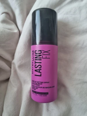 Maybelline Lasting Fix Face Mist - Maybelline Lasting Fix Face Mist i en snygg rosa flaska med svart spraymunstycke och lock. Ger en matt finish och håller sminket på plats upp till 16 timmar. Innehåller 100 ml och är perfekt för att fixera din makeup hela dagen. Helt ny