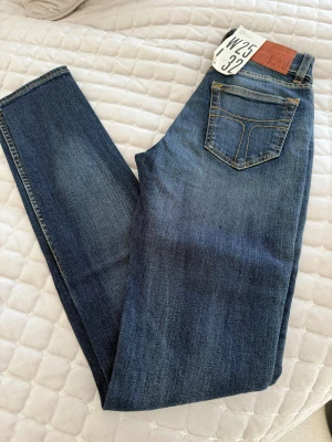 Tiger jeans slim fit  W25 L32 - Snygga klassiska blå jeans från Tiger slim fit och kontrastsömmar. Modellen har fem fickor. Perfekt passform och tidlös stil för dig som gillar slim fit