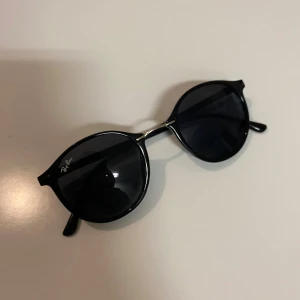Ray-Ban - Snygga Ray-Ban RB4242 solglasögon med rund form och svarta bågar. Glasen är mörka och ger en cool vibe. Diskret Ray-Ban-logga på linsen och sidan. Bågarna är i plast med metall-detaljer vid gångjärnen. Perfekt för dig som gillar klassisk stil. PRISET KAN DISKUTERAS.