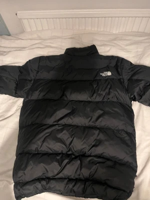 Svart pufferjacka från The North Face - Säljer en svart pufferjacka från The North Face. Riktigt fint skick och en väldigt varm jacka som passar perfekt nu när det börjar bli vinter.