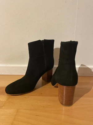 Svarta mockaboots med klack - Svarta Kiomi-boots i mocka med rund tå och träklack. Dragkedja på sidan. 