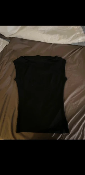 Kortärmade toppar - Två stilrena baslinnen från Nelly i storlek XXS, ett i vitt och ett i svart. Båda har ärmlös design med figurnära passform. 