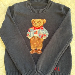 Mörkblå stickad tröja Polo Bear  från Ralph Lauren - Mörkblå stickad tröja med motiv av Polo Bear av Ralph Lauren. Storlek small vilket motsvarar ca 158/164. Använt men i gott skick. Helt och rent.   Hör av er  om ni har frågor!   Jag försöker i så stor utsträckning som möjligt posta inom 24h från köp. 