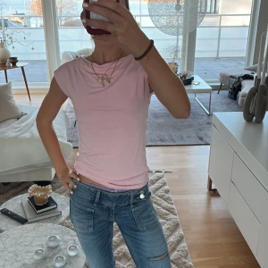 Ljusrosa ärmlös topp - Säljer en ljusrosa topp med rund hals och ärmlös design. Toppen har en slim passform och är tillverkad i mjukt bomullsmaterial som sitter skönt mot kroppen. Perfekt att styla med jeans eller kjol för en enkel och fräsch look.