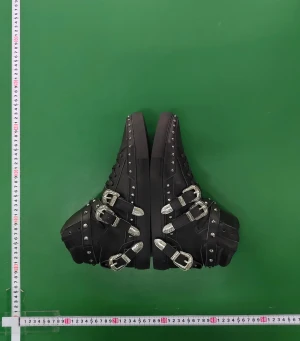 Svarta boots med nitar och spännen - Säljer ett par svarta boots i skinn med coola silverfärgade spännen och nitar längs kanterna. Skorna har snörning framtill, rund tå och platt sula. De har flera remmar med metallspännen och dekorativa detaljer som ger en edgy vibe. Perfekt för dig som gillar statement-skor.