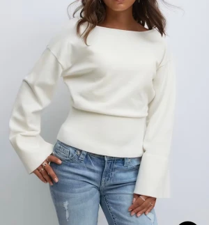 Vit långärmad tröja med breda ärmslut - Snygg vit långärmad tröja med breda ärmslut och båtringad hals. Tröjan har en ribbad midja som ger en schysst siluett och öppen rygg för en cool touch. Perfekt att styla med jeans eller kjol för en trendig look. Storlek 158/164.💕