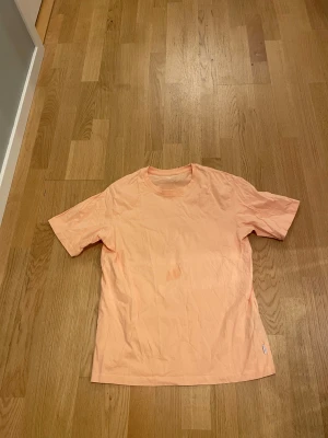 Ljusrosa t-shirt från Jack & Jones - Säljer en ljusrosa t-shirt från Jack & Jones Essentials i storlek S. T-shirten är tillverkad av ekologisk bomull, har rund hals och korta ärmar. Enkel och clean design utan mönster eller detaljer, perfekt för en chill stil.