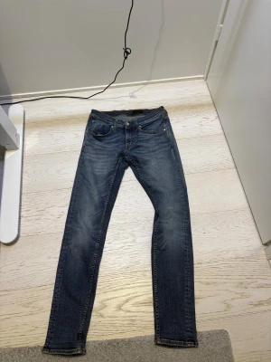 Tiger of Sweden skinny jeans - Snygga blå jeans från Tiger of Sweden med klassisk femficksdesign och skinny fit. Jeansen har en mörk tvätt med lätt slitning och bruna sömmar samt läderpatch bak. Perfekta för dig som gillar en smal siluett och stilren look.