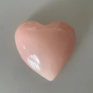 Handskuren hjärtformad alabaster - Säljer en handskuren hjärtformad prydnad i äkta alabaster från Italien. Den är ljusrosa och har en blank yta som reflekterar ljuset snyggt. Hjärtat är ca 9 cm långt och har en mjuk, rundad form. Perfekt som dekoration eller present till någon du gillar.