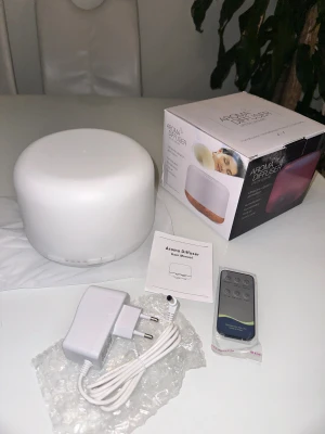 Aroma Diffuser Ultrasonic luftfuktare luftrenare  - Aroma Diffuser med ultraljudsteknik, fjärrkontroll och strömadapter. Perfekt för att sprida doft och skapa en avslappnande atmosfär. Komplett med originalförpackning och manual. Produkten ser ut att vara i nyskick utan synligt slitage.Aroma Diffuser med fjärrkontroll och manual. 🎁 