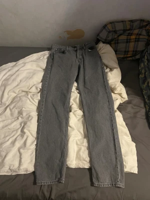 Jeans grå Jack and Johns slim fit  - Säljer ett par grå Jack and Johns  jeans med klassisk straight fit och fem fickor. Jeansen har knappgylf och är tillverkade i slitstarkt denim. Perfekt för dig som gillar en tidlös look med lite vintage-vibe.