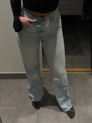 Ljusblå wide jeans från Gina Tricot - Säljer ett par ljusblå jeans från Gina Tricot med breda ben och råa kanter vid bensluten. Modellen har hög midja och är tillverkad i jeansmaterial. Använda men i fint skick, ord pris 500kr