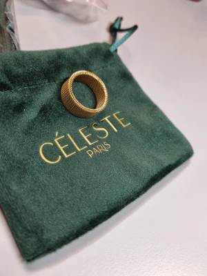 Guldfärgad ring från Céleste Paris 18k guld - Snygg guldfärgad ring från Céleste Paris 18k guld med ett coolt meshmönster runt hela ringen. Den har en bred och rund form som ger ett lyxigt och trendigt intryck. Perfekt accessoar för dig som gillar statement-smycken och vill sticka ut.