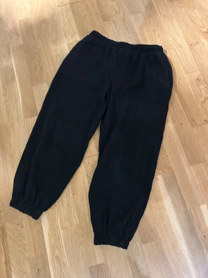 Svarta mjukisbyxor från H&M, storlek S - Svarta mjukisbyxor från H&M i storlek S. Byxorna har resår i midjan och vid bensluten, samt snörning framtill. Materialet är en mix av bomull och polyester, vilket gör dem mjuka och sköna. Perfekta för chill eller träning.