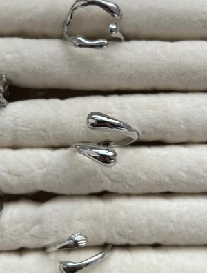Modern silverring med droppform - Snygg och stilren ring i silverfärgad metall med två droppformade ändar. Ringen har en öppen design som ger en cool och modern känsla. Perfekt accessoar för att lyfta din outfit med en unik touch.