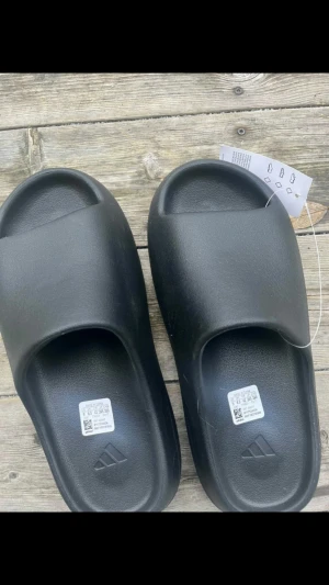 Svarta yeezy slides - Endast använda inomhus så helt nytt skick nästan, de är storlek 42 men passar för 40/41 och de är därför jag säljer dem