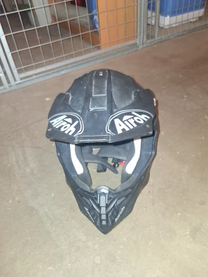 Svart crosshjälm från Airoh - Säljer en svart crosshjälm från Airoh med coola vita loggor och detaljer. Hjälmen har en sportig och kantig form, ventiler och vadderad insida med inslag av neonfärg. Perfekt för dig som gillar motocross och vill ha en hjälm med grym stil.säljer för jag har köpt en ny hjälm.Har dock några repor. PRISET ÄR INTE HUGGET I ETT STEN