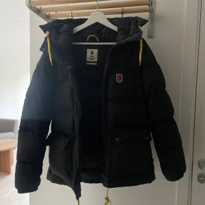 Fjällräven dunjacka - Säljer min svarta dunjacka från fjällräven, endast använd under förra vintern. Inga slitningar eller defekter. 6999kr nypris. Tvättas självklart innan jag skickar iväg den💕 Passar mig som är S/M men ville få plats med en stickad tröja under☺️