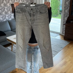 Grå Jeans från Jack N Jones - Säljer ett par riktigt snygga och fräscha gråa jeans från Jack & Jones, modell loose fit men sitter mer som regualar skulle jag själv säga. Storlek 28/30. Har en skada som synns på 3e bilden men skadan är mycket minimal. Skriv vid minsta fundering😄🙌🏼